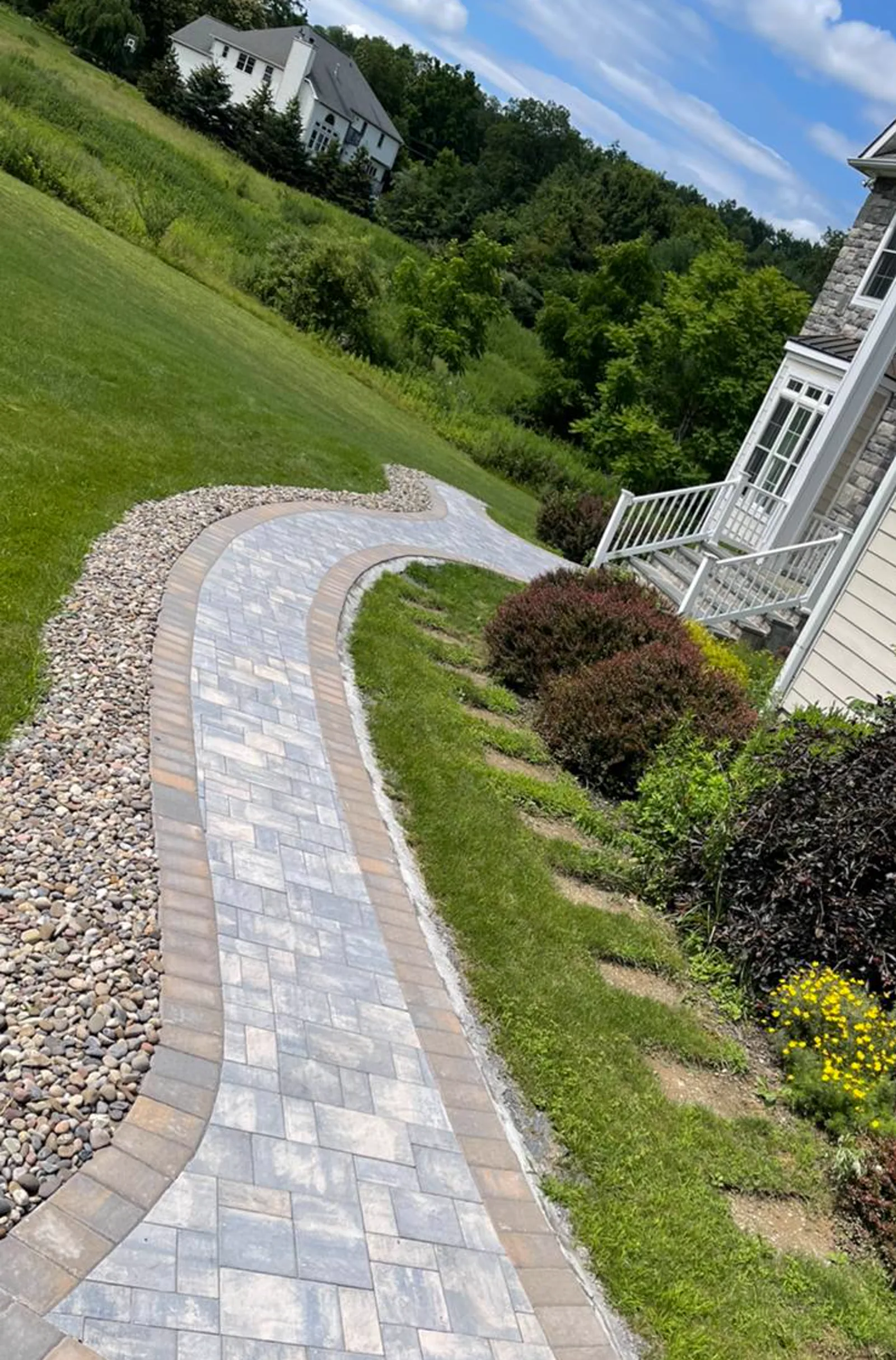Curved paver walkway beside a residential home
