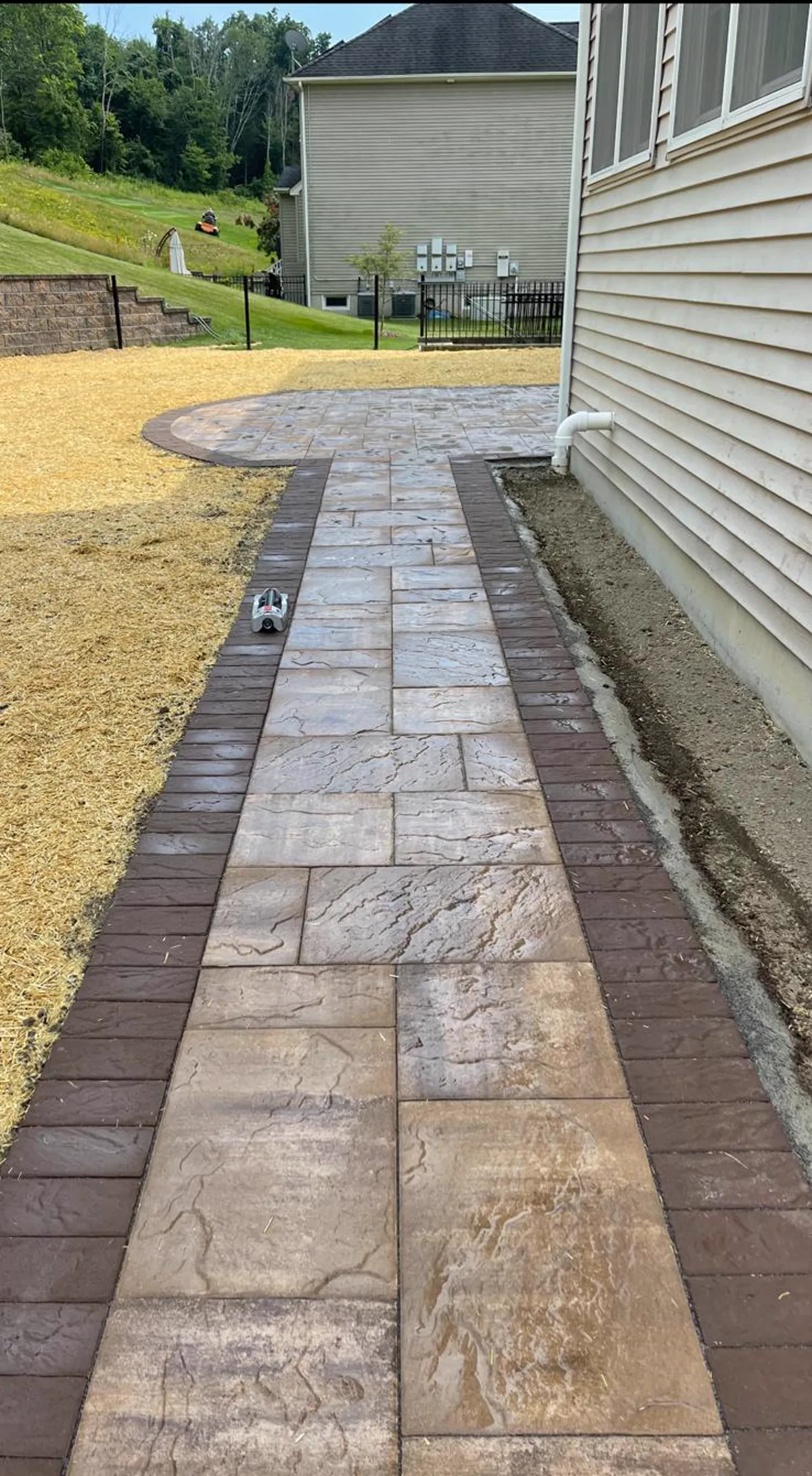 Paver walkway with contrasting border beside a residential home